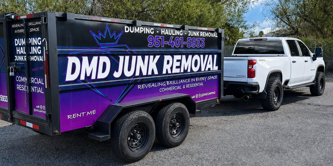 Una traila de dompe de DMD Junk Removal enganchada detrás de una pickup blanca en un terreno de grava