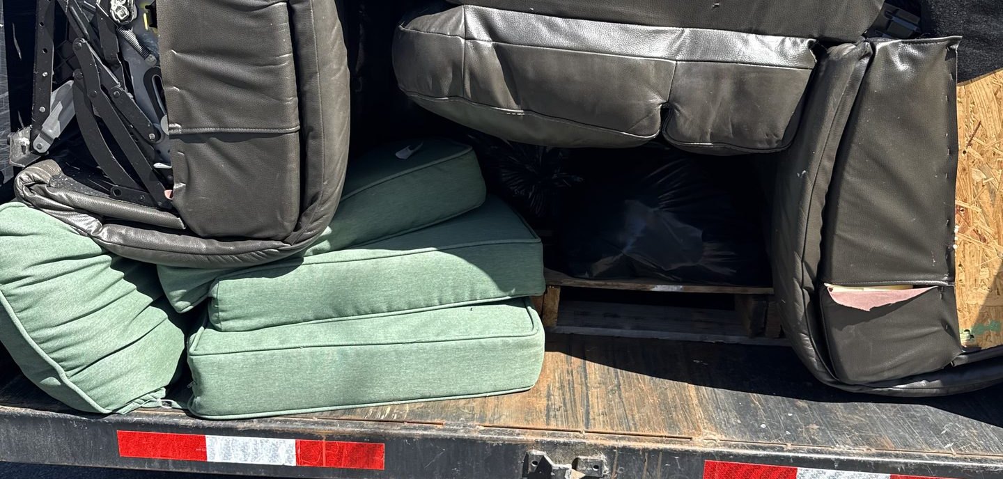 Leather sectional cushions and patio cushions loaded onto the bed of a DMD dump trailer