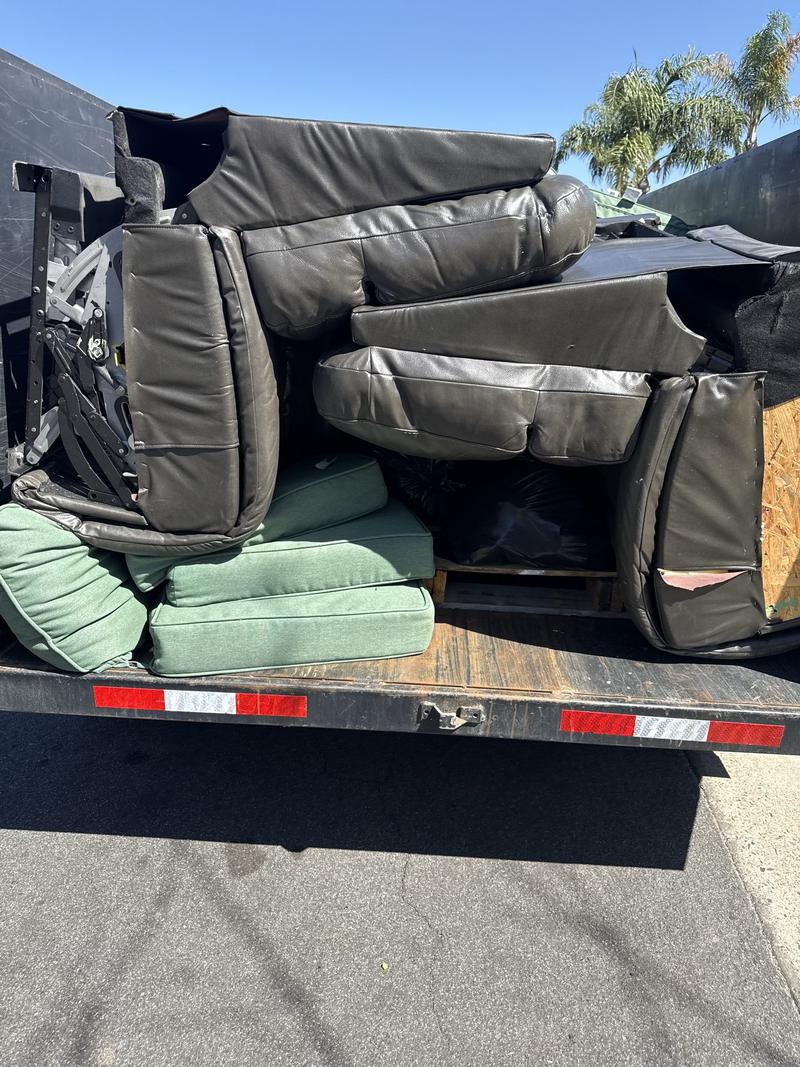 Leather sectional cushions and patio cushions loaded onto the bed of a DMD dump trailer