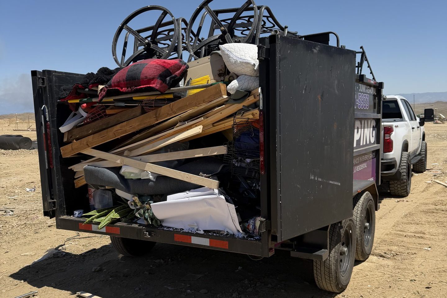 The back of a DMD dump trailer packed with lumber, framing offcuts and remodel debris