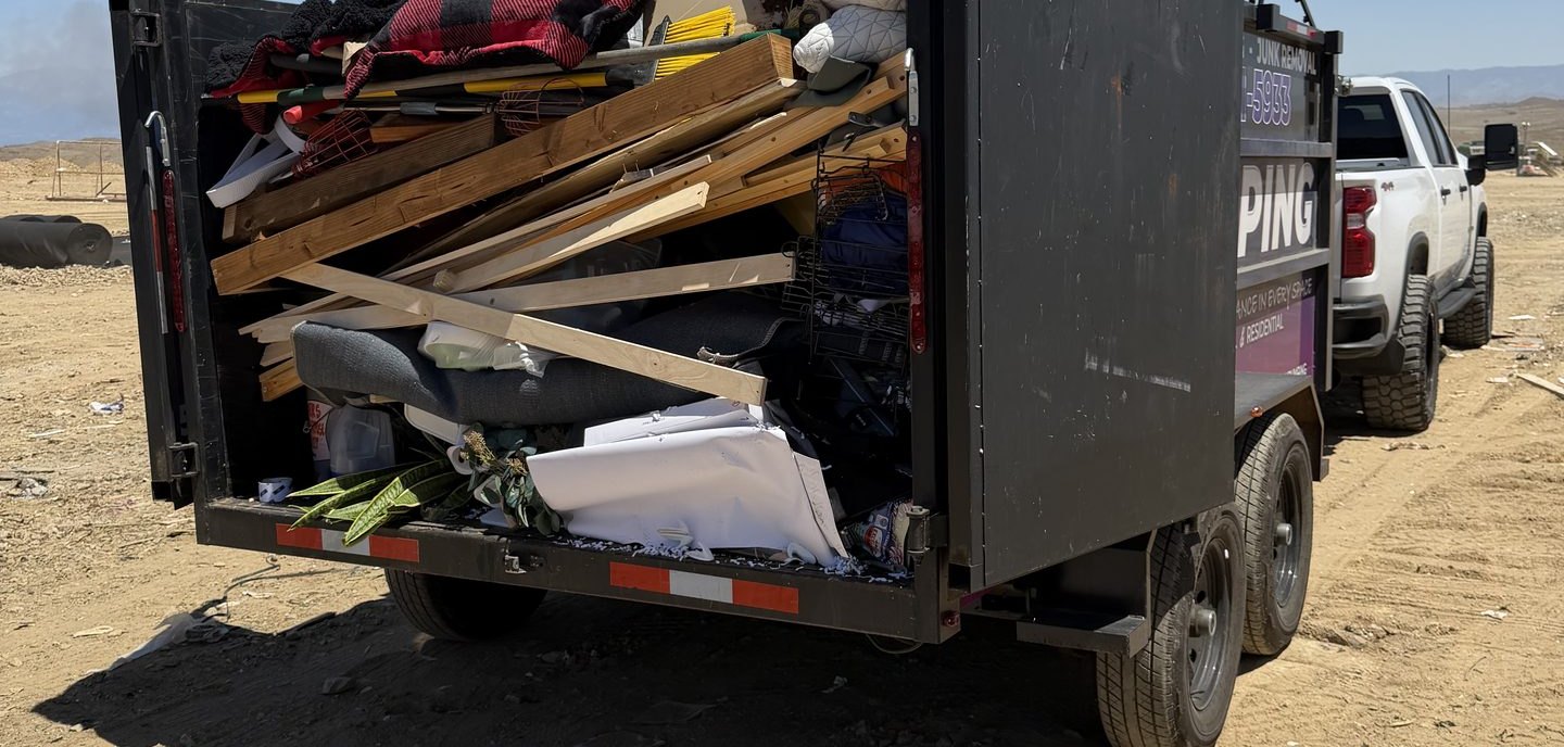 The back of a DMD dump trailer packed with lumber, framing offcuts and remodel debris