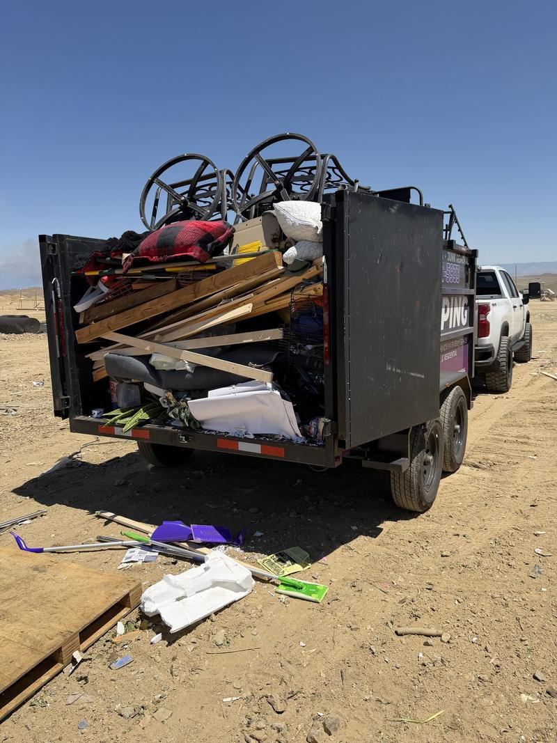 The back of a DMD dump trailer packed with lumber, framing offcuts and construction debris